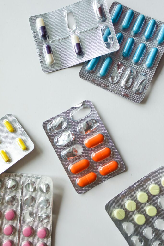 Various blister packs of colorful pills and capsules on a white surface.